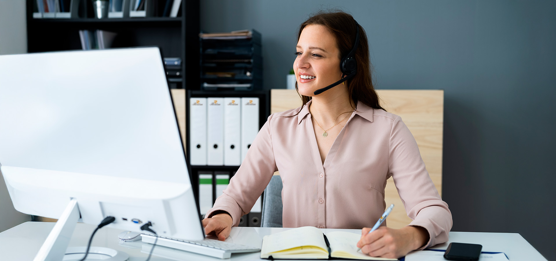 Eine Frau an einem Schreibtisch mit einem Headset auf